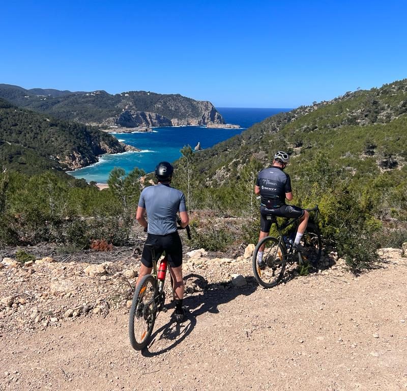 Gravel cyclist riding an unpaved red dirt road through the pine forests of Ibiza